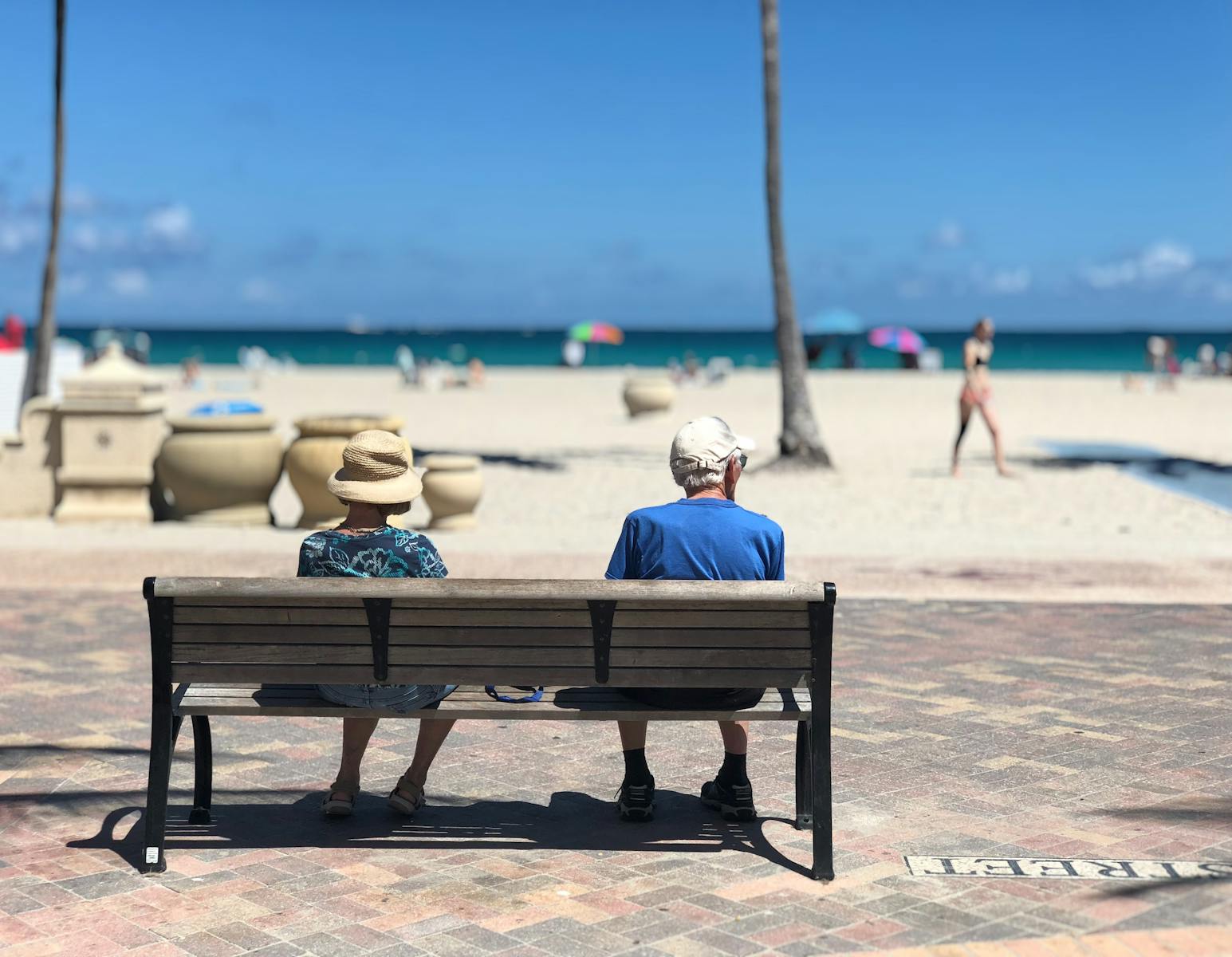 Senior couple sitting on a bench enjoying a sunny day at Hollywood Beach, Florida.